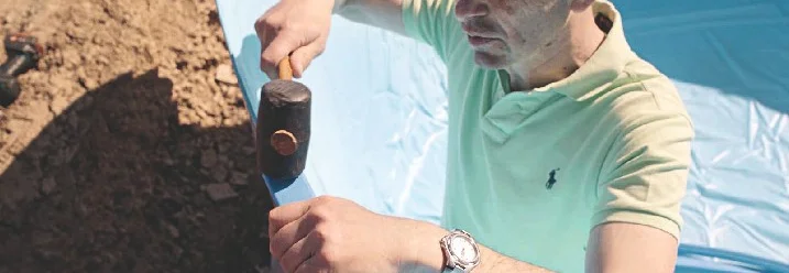 Person baut mit Hammer einen Pool auf.